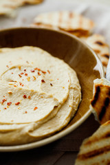 Homemade traditional Middle East appetizer creamy hummus or chickpea dip served with pieces of toasted pita in vintage ceramic plate close-up on white background.Healthy organic vegan snacks