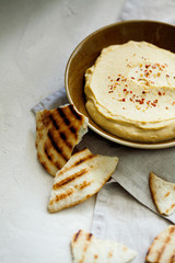 Homemade traditional Middle East appetizer creamy hummus or chickpea dip served with pieces of toasted pita in vintage ceramic plate on white background top view.Healthy organic vegan snacks