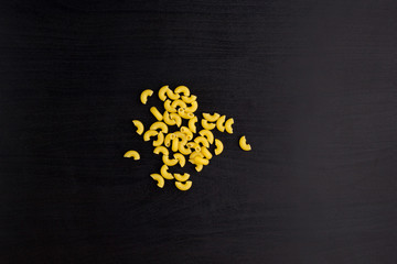 A pile of pasta horns on black background