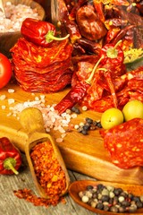 sausage or salami with chili pepper with herbs on wooden table. Spicy salami with chili. Unhealthy Fat Food.