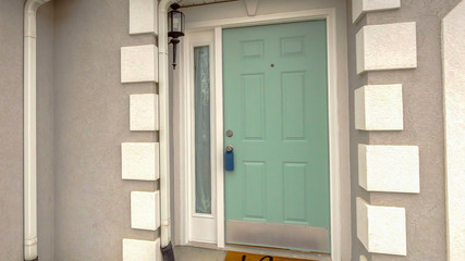 Clear Panorama Green front door with sidelight on the facade of home viewed against cloudy sky