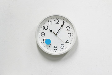 White clock on white concrete wall background.