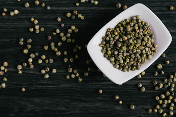 Green peppercorns in white bowl on wooden background