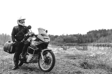 Naklejka premium Mężczyzna motocyklista z motocyklem przygodowym. Poza drogą. Wycieczka motocyklowa. enduro Traveling, Lifestyle Koncepcja outdooru dual sport. odzież ochronna, czarno-biała. kask motocyklowy.