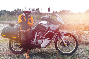 Fototapeta premium Biker girl wearing a motorcycle outfit, protective clothing, equipment, adventure touristic motorbike with side bags. outdoor travel, active traveler, enduro, off road