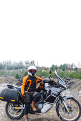Fototapeta na wymiar Biker girl wearing a motorcycle outfit, protective clothing, equipment, adventure touristic motorbike with side bags. outdoor travel, active traveler, vertical photo