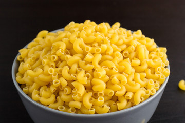 black background with italian raw pasta horns in bowl with copy space
