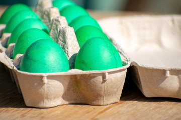 Green eggs on the table in the package on a sunny Easter holiday day