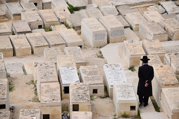 Hombre judío ortodoxo paseando solo por el cementerio de Jerusalén, Israel, Medio oriente.