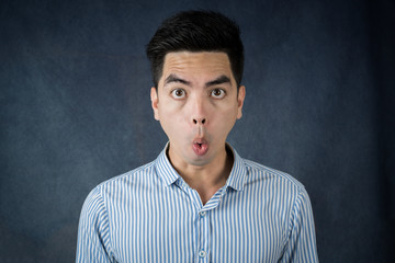 Portrait excited or Shocked  handsome young asian man wearing a blue shirt isolated on dark wall background.  Asia people.