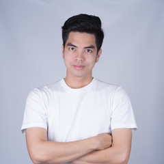 Portrait handsome young asian man wearing a white T-shirt smile and look happy isolated on grey background. Asian man people. business success concept.