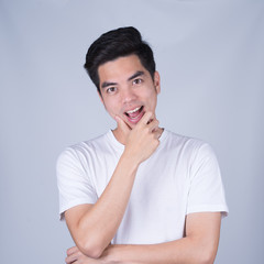 Portrait handsome young asian man wearing a white T-shirt smile and look happy isolated on grey background. Asian man people. business success concept.