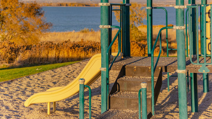 Clear Panorama Slide on a playground overlooking a serene blue lake on a sunny day