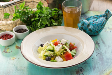 Fresh Greek salad with olives tomato feta cheese cucumber and onion on blue wooden table