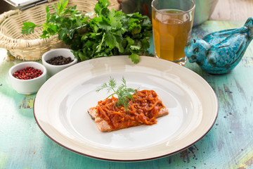 Appetizing roasted salmon steak with carrot sauce on blue wooden table