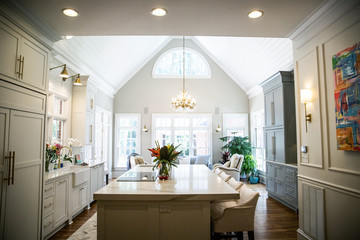 Open Concept Elegant and Spacious Kitchen with Marble Countertops, Chandelier, and Two Toned Cabinets