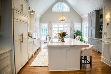 Open Concept Elegant and Spacious Kitchen with Marble Countertops, Chandelier, and Two Toned Cabinets