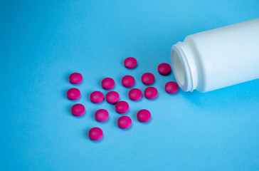 Tablets and an open bottle on a blue background. Concept medicine, pharmacology. Free space for text