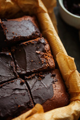 Delicious fresh baked healthy vegan moist dark chocolate brownies dessert or sponge cake with coffee frosting cut in squares on baking paper top view.Vertical orientation.Selective focus