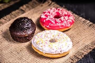 Sugar coated donuts and cupcakes are on burlap.