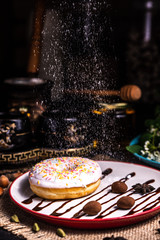 Donut in icing with nuts in a chocolate truffle in a restaurant. Powdered icing.