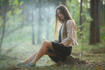 Vape teenager. Young cute girl in casual clothes smokes an electronic cigarette outdoors in the...