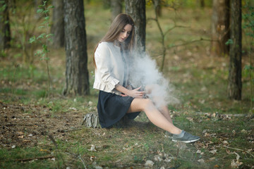 Vape teenager. Young cute girl in casual clothes smokes an electronic cigarette outdoors in the...
