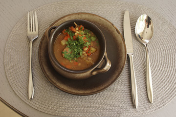 Soup in a clay plate on a gray table background