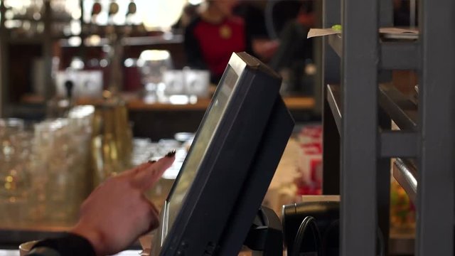 Close-up of the waiter's hand on the touch screen in the cafe, registration and payment of the order. Hand of the waiter near the working touch screen monitor.
