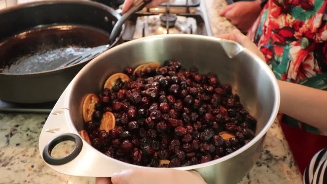 Side view Approaching from bottom to top. Putting some raisins in the pot. Women making Mole in Puebla Mexico. Central America. Two people grinding some ingredients. Cooking Traditional recipe.