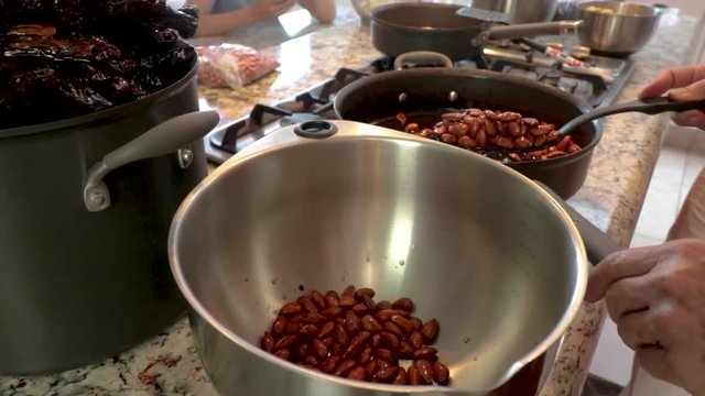Front view Approaching. Putting some raisins in the pot. Women making Mole in Puebla Mexico. North America. Two people grinding some ingredients. Cooking Traditional recipe.