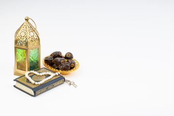 Lantern, Dates, Koran and Rosary on white background with selective focus and crop fragment. Ramadan, Religion and Copy space concept
