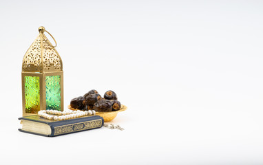 Lantern, Dates, Koran and Rosary on white background with selective focus and crop fragment. Ramadan, Religion and Copy space concept