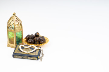 Lantern, Dates, Koran and Rosary on white background with selective focus and crop fragment. Ramadan, Religion and Copy space concept