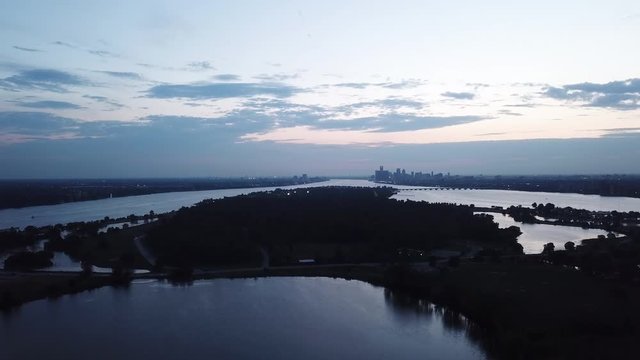 Belle Isle Detroit aerial view at sunset on a summer day. Bridge, buildings, boats visible in the distance. Island silhouette on the Detroit river with the Detroit skyline in the background.