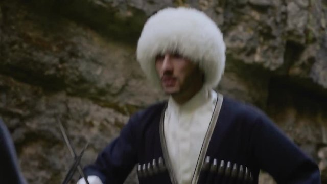 warrior mountaineers in Dagestan fur papakhas and circassians demonstrate highland dagger battle in gorge closeup