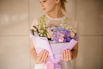Beautiful girl with ponytail holds bouquet in purple wrapping