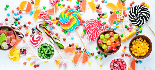 Colorful candies, jelly and marmalade on a white wooden background. Sweets. Top view. free copy...