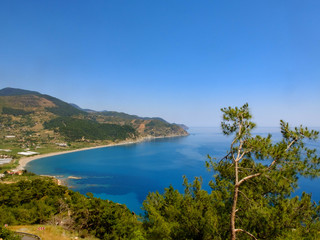 Fototapeta na wymiar Beautiful picturesque bay at Mediterranean sea, clear sky and pine trees on the rocky slopes in the sunny afternoon