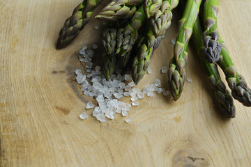 bunch of fresh asparagus with coarse sea salt on a wooden background. veganism and raw foods