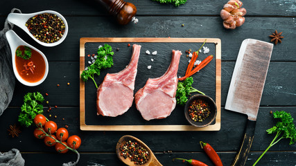 Raw pork steak on the bone. On a stone board with spices and herbs. Top view. Free space for your...
