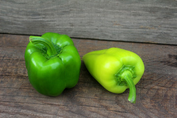 Two Ripe Green pepper lying on a wooden background. Close up view from top.