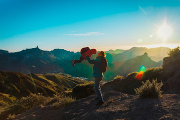 Father and little daughter enjoy travel in sunset mountains