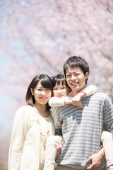 Naklejka premium 桜の前でおんぶをする親子