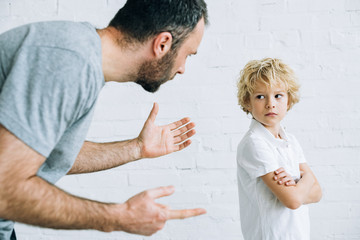 partial view of bearded father scolding son at home