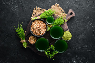The juice from the green sprouted wheat, and wheat grains. On a black background. Micro Green. Healthy food. Top view. Free space for your text.