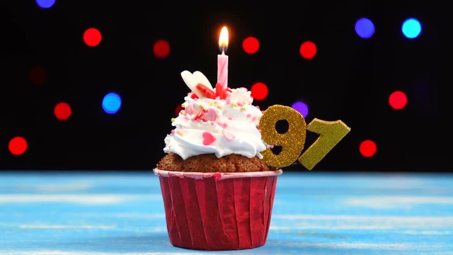 Delicious birthday cupcake with burning candle and number 91 on multicolored blurred lights background