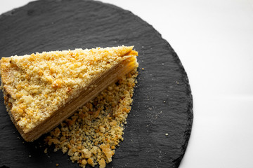a piece of honey cake on a stone plate with crumbs