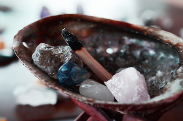 Abalone Shell with Palo Santo, and filled with healing crystals. Rose Quartz, Smokey Quartz, Sodalite, and Clear Quartz.  Burning palo santo in a abalone shell, being held. Variety of crystals shell
