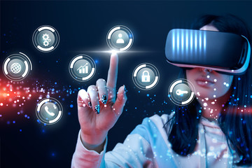 selective focus of young woman in virtual reality headset pointing with finger at glowing cyber icons on dark background